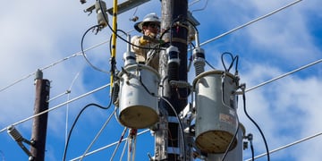 electricity wires, blue sky, wwhite cloud, man in helmet fixing transformer