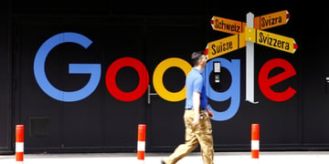 khaki throusers, blue t-shirt, white male, google logo, light orange pointers to Switzerland.