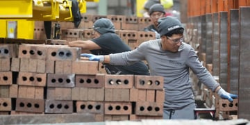 Workers package and cube pallet bricks, grey outfits