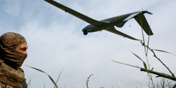 white soldier in field with tall grass, blue sky, white clouds, huge military drone in the sky