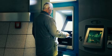 older man standing at the atm
