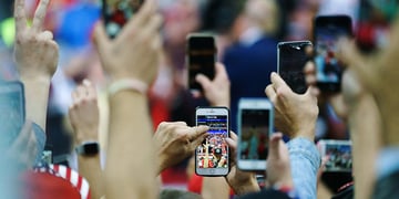 Attendees hold up their smartphones to take videos during a rally with U.S. President Donald Trump in Minneapolis
