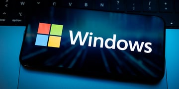 The Windows logo appears on the screen of a smartphone placed on a computer keyboard