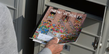 Person holding New Yorker magazine near mailbox