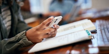 A student scrolling on a phone and studying