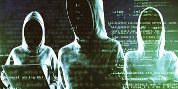 Three hackers in hoodies surrounded by the black background with snippets of green code.