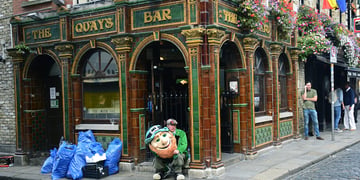 A man dressed in a leprechaun costume hired to attract customers to a Dublin, Ireland, pub takes a break in front of the pub in Dublin's Temple Bar district.