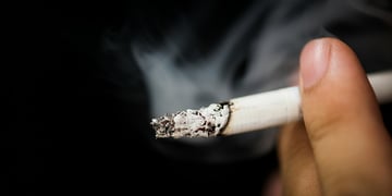 A person's hand holding a cigarette.