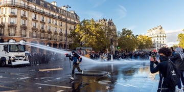 Videographer runs through water cannon while student films with phone