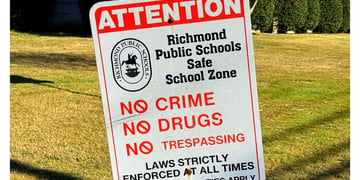 Richmond City Public School sign in forefront, high school in background