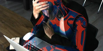 A worried humanoid robot looking at a laptop screen.