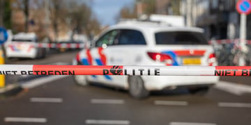 police security tape reading "politie" in Dutch; police car in the background