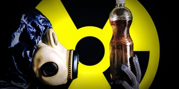 A man in a gas mask holds plastic bottle with dirty water