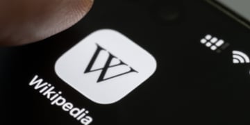 Finger press Wikipedia app icon close up view on smartphone screen