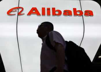 Man walks past Alibaba logo