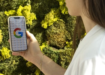 Google logo on white smartphone screen, white t-shirt, white female, long dark brown hair, green