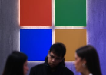 microsoft logo, red, green, blue, yellow squares, two white blurry women, one white blurry man.