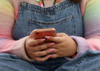 pink nails, smartphone, jeans, rainbow color top