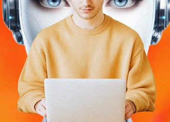 A person sitting at their laptop, big robot's head behind it