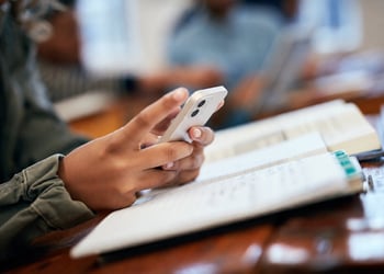 A student scrolling on a phone and studying