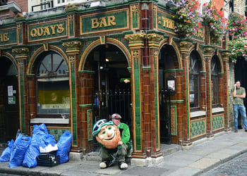 A man dressed in a leprechaun costume hired to attract customers to a Dublin, Ireland, pub takes a break in front of the pub in Dublin's Temple Bar district.
