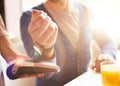 Hand of businessman with smartwatch over payment machine held by waitress