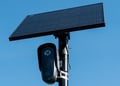 black flock camera, clear blue sky, black solar panel