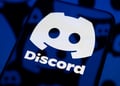 dark smartphone screen reflects one big white discord logo, little darker ones are in the back