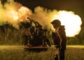 ukrianian soldier in uniform, helmet, white male, night time field, explosion artilery