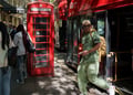 london, black man in light green throusers and shirt, red telephone booth