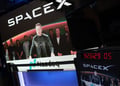 spaceX logo, elon musk on big screen, taking in video, black jacket, nasdaq