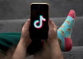 A child holds a smartphone displaying the TikTok logo in an arranged photograph in Sydney, Australia