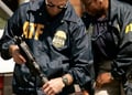 2 ATF agents wearing jackets with logo holding guns